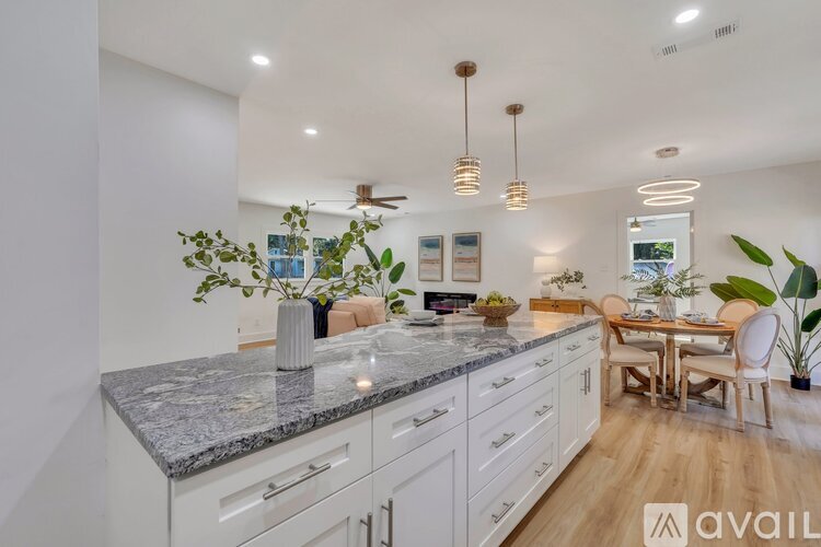 A kitchen with a marble countertop and a dining area with a table and chairs.