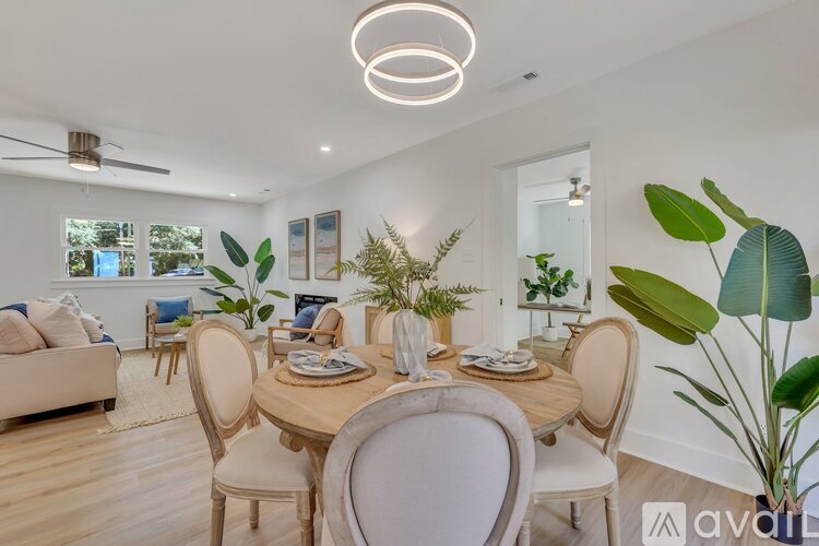 A well-lit dining room with a round table surrounded by chairs.