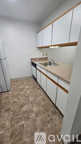 A kitchen with a refrigerator, sink, and cabinets.