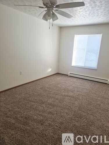 A room with a ceiling fan and a window with blinds.