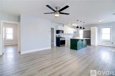 A spacious kitchen and living room with a ceiling fan and hardwood floors.