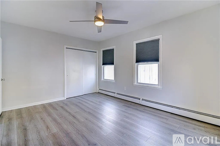 A room with a ceiling fan and two windows.