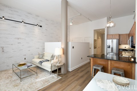 A modern kitchen with a white brick wall and a white sofa with a yellow cushion.