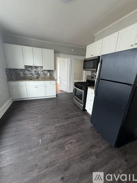 A kitchen with black appliances and white cabinets.