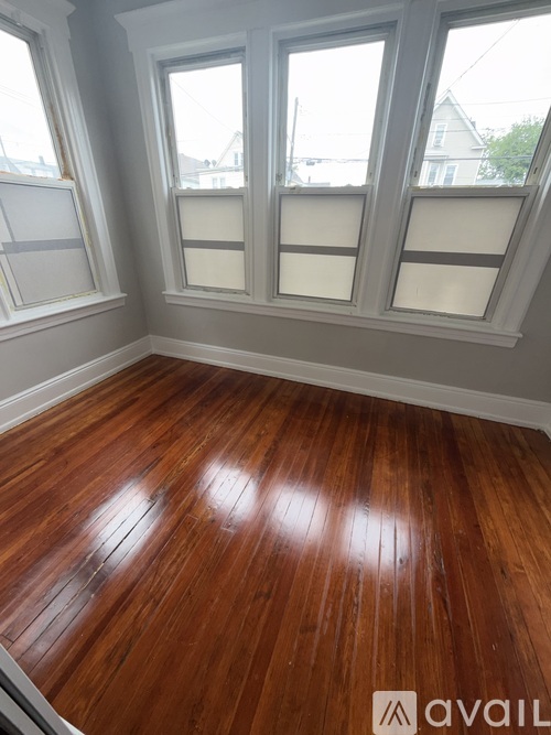 A room with wooden floors and three windows.