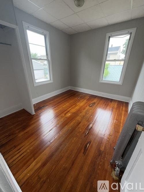 A room with wooden floors and two windows.