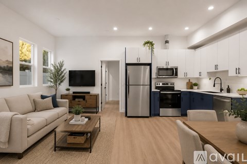 A modern kitchen and living room with a couch, coffee table, and a TV.