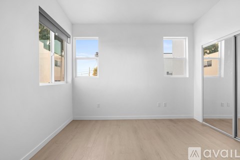 A spacious room with wooden flooring and white walls.