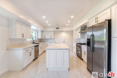 A modern kitchen with white cabinets and stainless steel appliances.