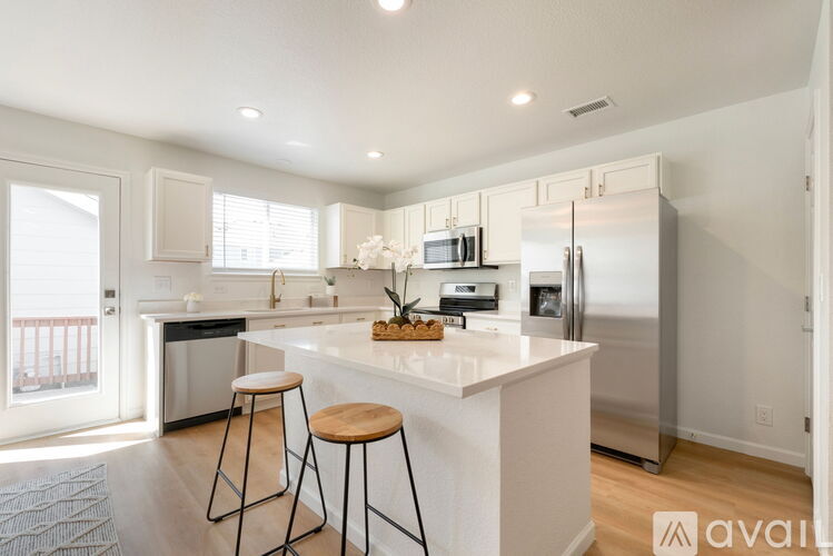 A kitchen with white cabinets and a white island with two stools.