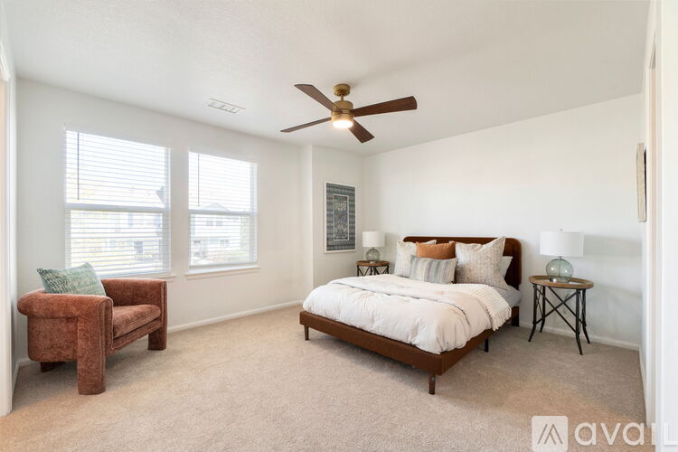 A bedroom with a bed, chair, and ceiling fan.