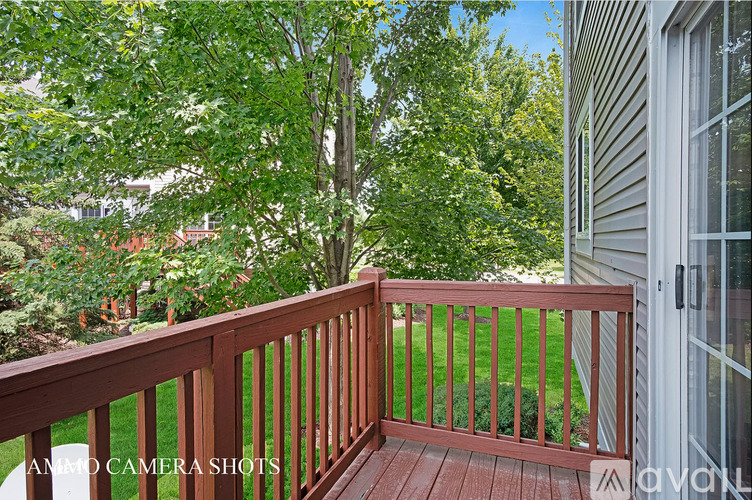 A wooden deck with a view of a tree and a house.