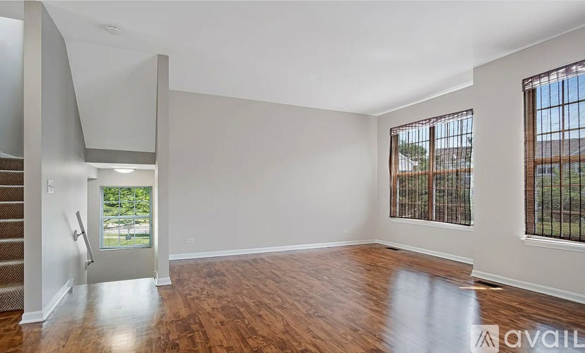 A spacious room with wooden floors and a staircase leading to another level.