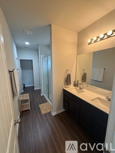 A bathroom with a mirror, sink, and wooden floors.