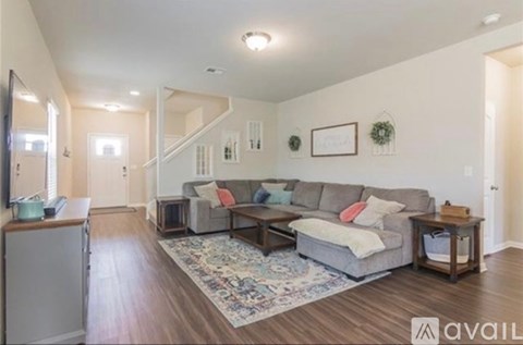 A living room with a grey couch and a rug.