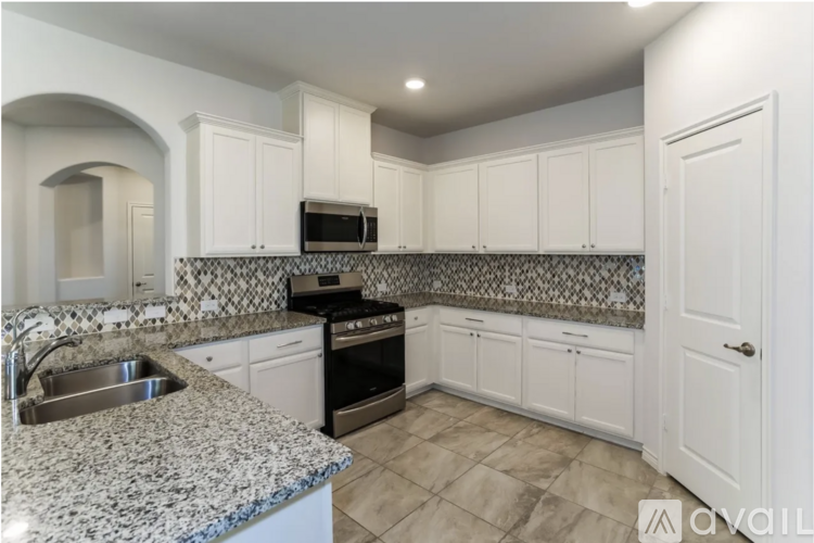 A kitchen with white cabinets and a granite countertop.