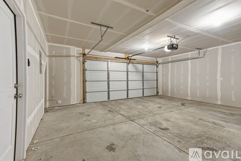 A spacious garage with a closed white door and a ceiling fan.