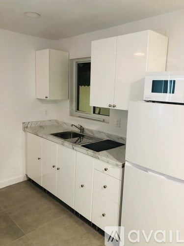 A kitchen with white cabinets and a marble countertop.
