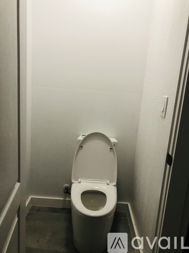 A white toilet in a small, narrow bathroom.