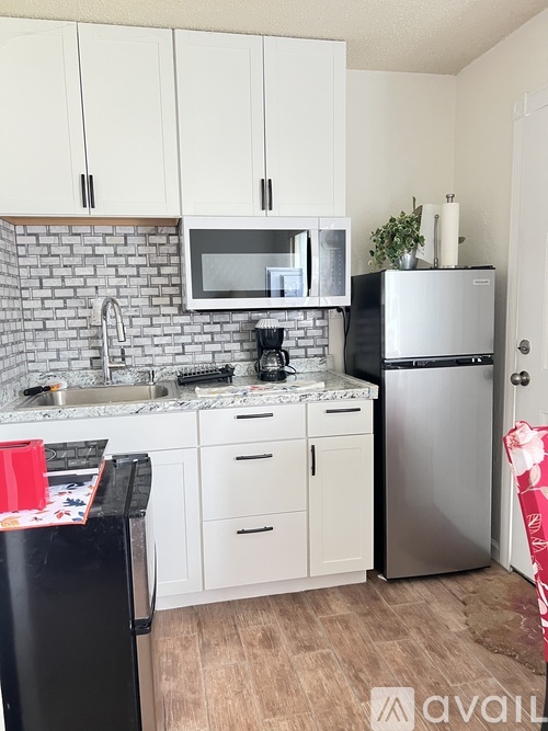 A kitchen with white cabinets and a black fridge.