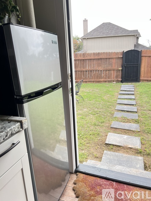 A white refrigerator is in the kitchen next to a window.