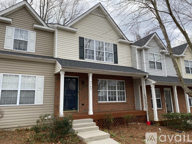 A two-story house with a front porch and a garage door.
