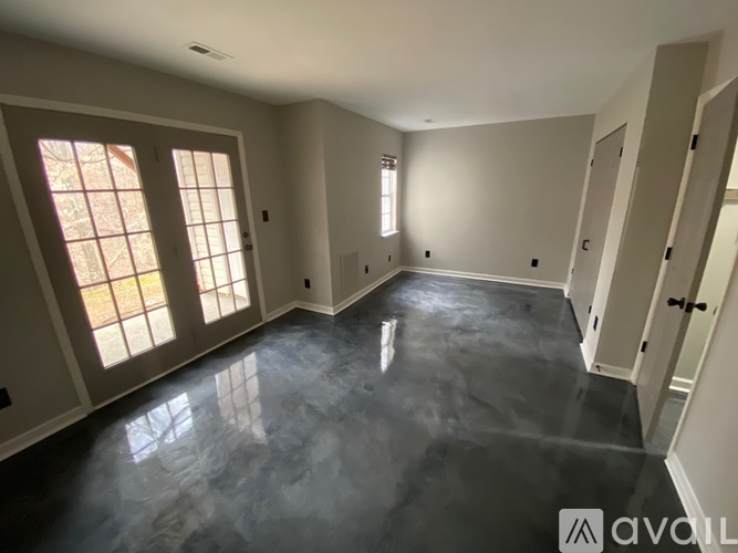 A spacious room with a polished concrete floor and large windows.
