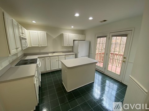 A kitchen with white cabinets and a black tile floor.