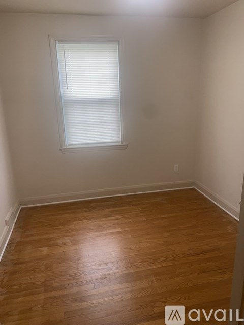 A room with wooden flooring and a window with blinds.