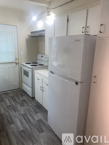 A kitchen with white appliances and a grey floor.
