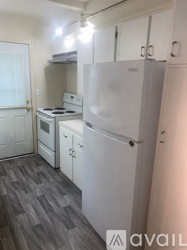 A kitchen with white appliances and a grey floor.