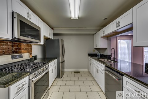 A kitchen with white cabinets and a brick wall.