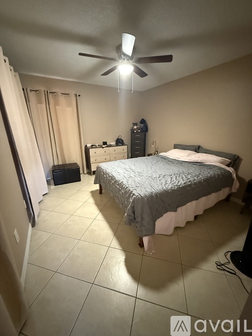 A bedroom with a bed, dresser, and a ceiling fan.