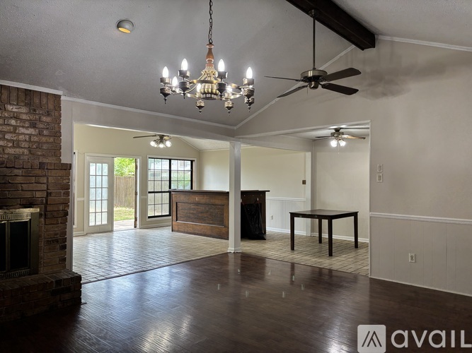 A living room with a brick fireplace and a chandelier.