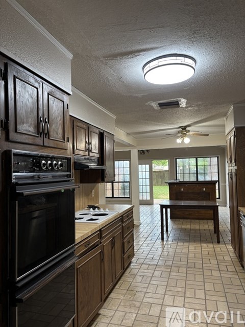 A kitchen with a black oven and wooden cabinets.