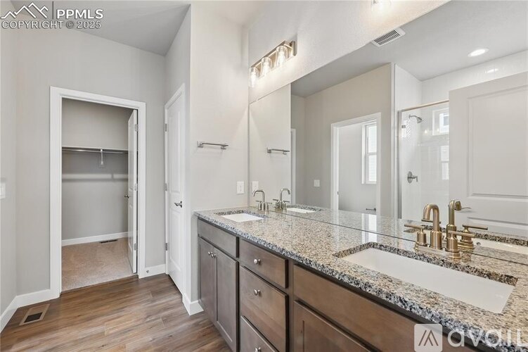 A bathroom with a sink, mirror, and wooden floors.