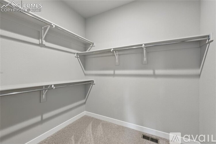 A room with white walls and a carpeted floor with two metal shelves.