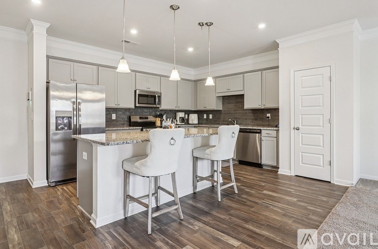 A kitchen with a white island and two chairs.