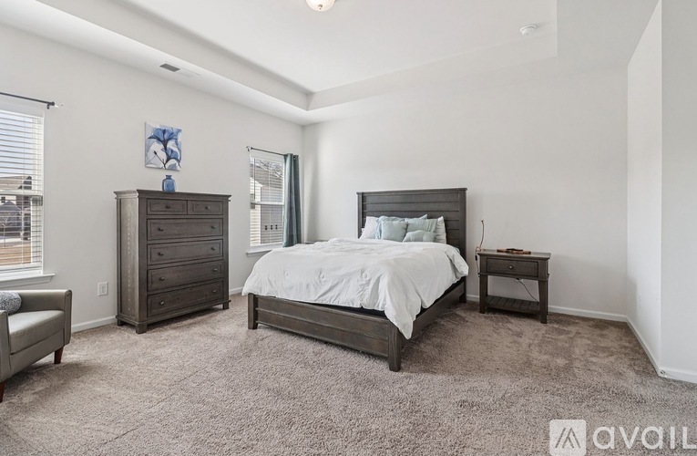A bedroom with a bed, nightstand, and dresser.