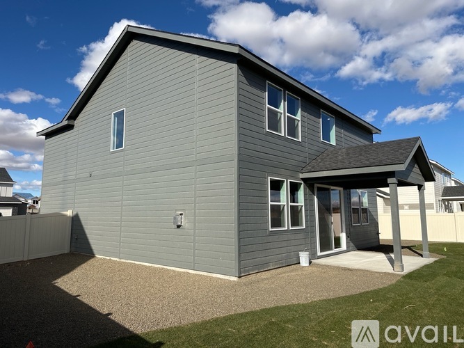 A grey house with a white bucket on the ground.