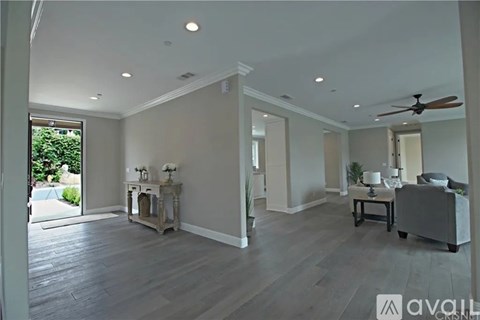 A spacious living room with a grey sofa and a wooden floor.