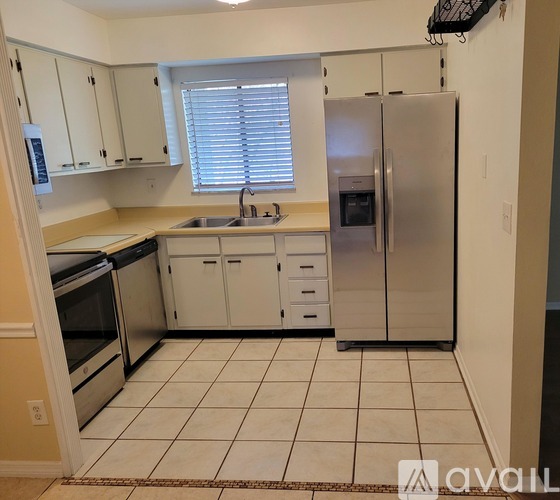 A kitchen with white cabinets and a stainless steel refrigerator.