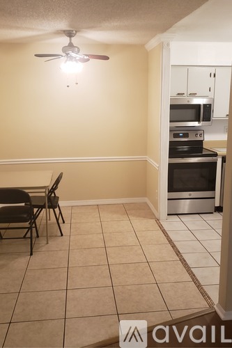 A kitchen with a table and chairs in the foreground and a microwave, oven, and stove in the background.