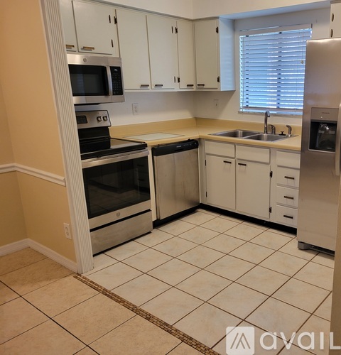 A kitchen with white cabinets and a tiled floor.