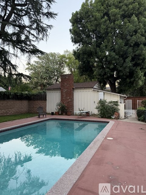 A pool surrounded by a brick wall and trees.