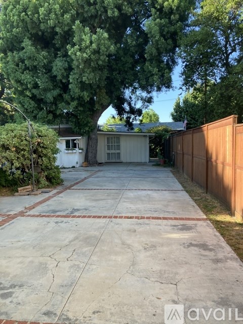 A backyard with a concrete patio and a wooden fence.