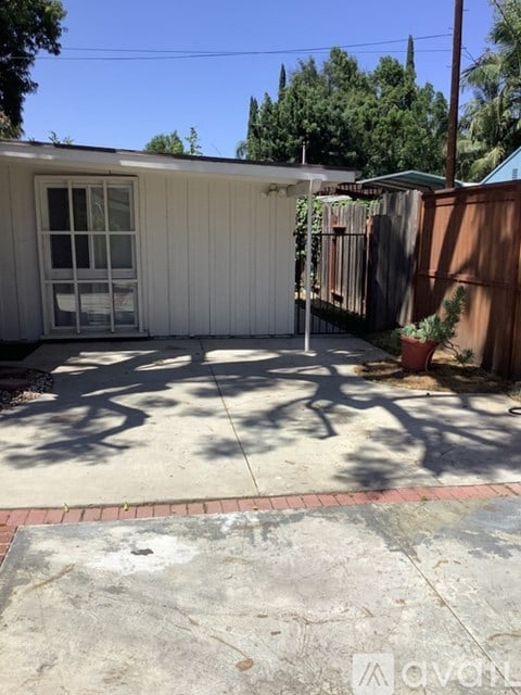 A small white house with a brown fence and a window.