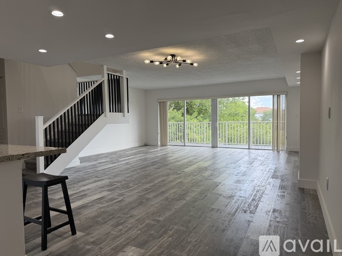 A spacious living room with a bar stool and a staircase.