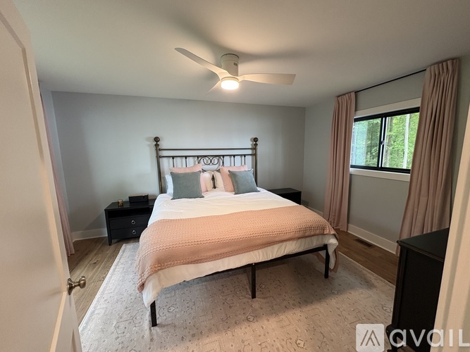 A bedroom with a bed, nightstand, and window.