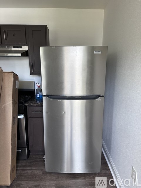 A silver fridge in a kitchen with a cardboard box beside it.